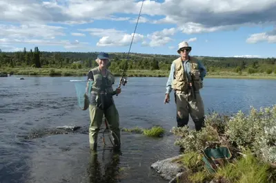 a couple of people standing in the water with a fish at Bualie Golsfjellet in Gol
