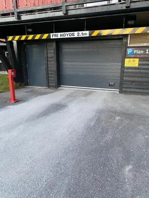 a garage with a garage door with a sign on it at Leilighet Beitostølen sentrum, terrasse og innendørs parkering in Beitostøl