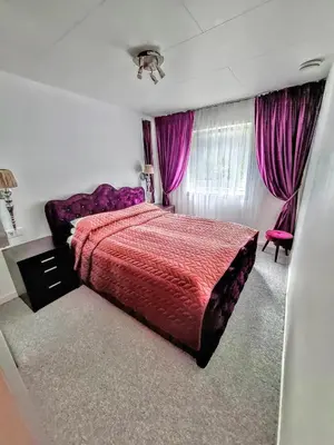 a bedroom with a red bed and purple curtains at Bergen Sunrise Terrace Apartment in Bergen