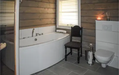 a bathroom with a tub and a toilet and a chair at Lovely Home In Hjartdal With Sauna in Hjartdal