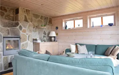 a living room with a blue couch and a stone wall at Cozy Home In Norheimsund With Sauna in Norheimsund