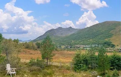 a bench sitting on a hill with mountains in the background at 4 Bedroom Cozy Home In Straumgjerde in Brunstad
