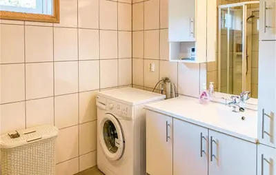 a bathroom with a washing machine and a sink at 4 Bedroom Cozy Home In Straumgjerde in Brunstad
