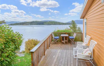 a wooden deck with chairs and a table with a view of the water at 1 Bedroom Nice Home In Skånevik in Skånevik