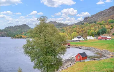 a small red house on the shore of a lake at 1 Bedroom Nice Home In Skånevik in Skånevik