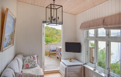 a living room with a couch and a tv on a porch at 1 Bedroom Nice Home In Skånevik in Skånevik