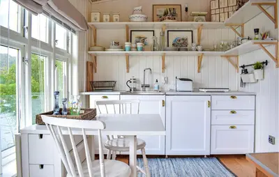 a kitchen with white cabinets and a table and chairs at 1 Bedroom Nice Home In Skånevik in Skånevik