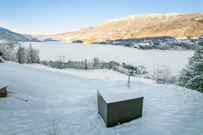 a box sitting in the snow next to a lake at Stamp and sauna! Small farm with fantastic view! in Favang