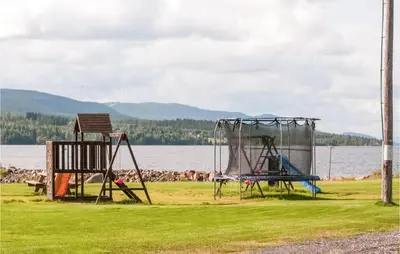a swing set and a playground next to the water at Stunning Home In Søre Osen in Midskogberget