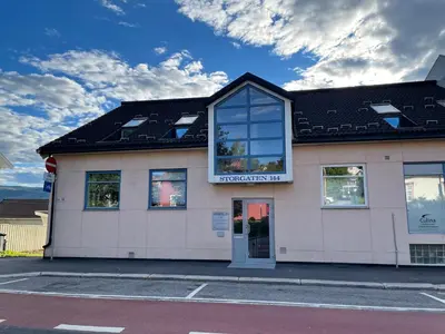 a white building with a black roof at Lovely apartment with parking in the heart of city in Lillehammer