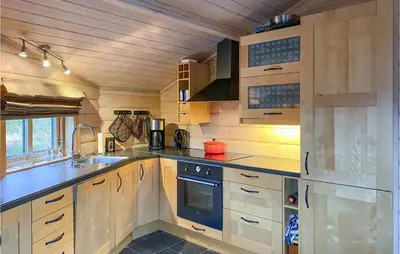 a kitchen with wooden cabinets and a stove at Cozy Home In Straumgjerde With Sauna in Brunstad