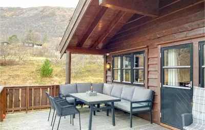 a patio with a table and chairs on a deck at Cozy Home In Straumgjerde With Sauna in Brunstad