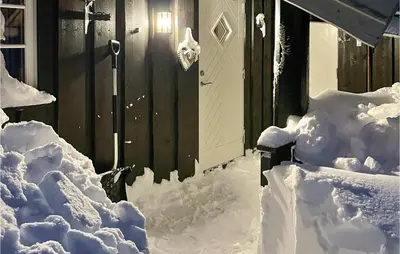 a house covered in snow next to a building at Stunning Home In Sjusjøen With Sauna in Sjusjøen