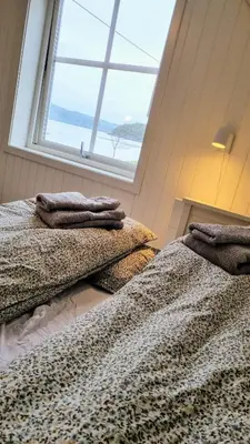 two beds in a room with a window at The Fjord House in Snofugl