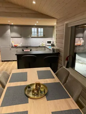 a kitchen with a wooden table with chairs and a counter at Fjelltun Lodge in Sogndal