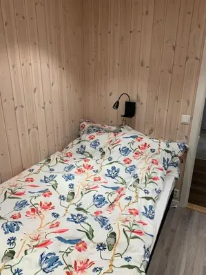 a bed with a floral comforter in a bedroom at Fjelltun Lodge in Sogndal