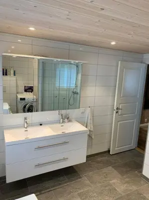 a bathroom with a sink and a mirror and a door at Fjelltun Lodge in Sogndal