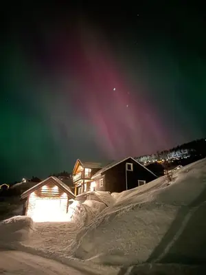 a house in the snow at night with the lights on at Fjelltun Lodge in Sogndal