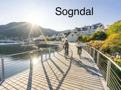two people riding bikes on a bridge over a body of water at Fjelltun Lodge in Sogndal