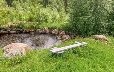 a bench sitting in the grass next to a pond at 2 Bedroom Gorgeous Home In Eggedal in Eggedal