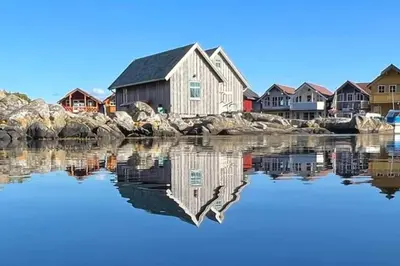 a house on the water next to some rocks at Exceptional Cottage 2 meters from the sea, possible to rent boat, Bekkjarvik, 60 km from Bergen in Gauksheim