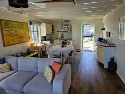 a living room with a couch and a table and a kitchen at Exceptional Cottage 2 meters from the sea, possible to rent boat, Bekkjarvik, 60 km from Bergen in Gauksheim