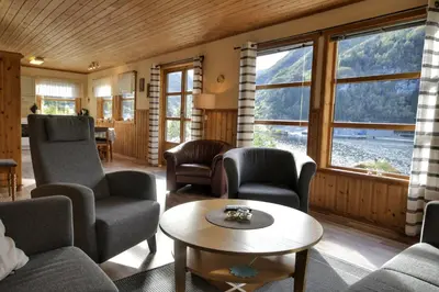 a living room with chairs and a table and windows at Fully equipped cabin by the fjord in Volda