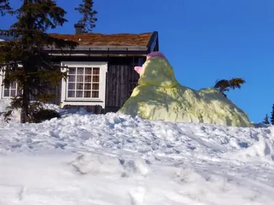 a house covered in snow in front of a house at Stor familiehytte på Småsætra, Sjusjøen in Sjusjøen