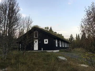a black barn with a white door in a field at Gålå Fjellhytte - cabin with sauna and whirlpool tub in Sør-Fron