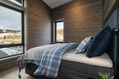 a bedroom with wooden walls and a bed with blue pillows at Riddertunets top notch in Beitostøl