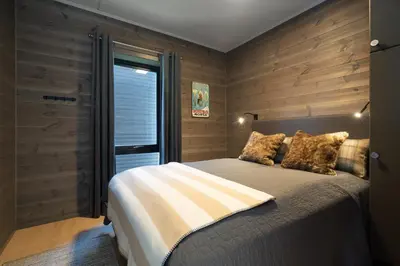 a bedroom with a bed and a wooden wall at Riddertunet deluxe in Beitostøl