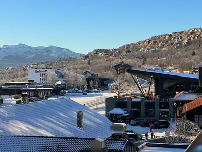 a snow covered parking lot with a mountain in the background at Riddertunet deluxe in Beitostøl