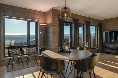 a dining room with a table and chairs and windows at Riddertunet deluxe in Beitostøl