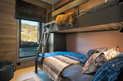 a bedroom with two bunk beds and a ladder at Riddertunet deluxe in Beitostøl