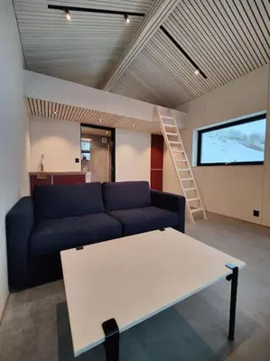 a living room with a blue couch and a table at Minihuset ved skogen in Isfjorden