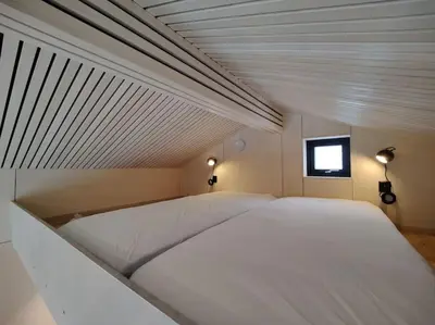 a large white bed in a room with a window at Minihuset ved skogen in Isfjorden