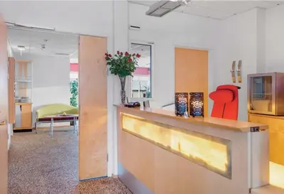 an office lobby with a reception counter and red chairs at Gjøvik Overnatting in Gjøvik