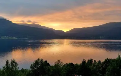 a sunset over a body of water with mountains at Rekdal in Vestnes