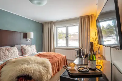 a bedroom with a bed and a bottle of wine on a table at Skåbu Fjellhotell in Skåbu
