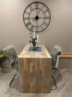 a table and chairs with a large clock on the wall at Gjestehus i Sogndal med utsikt over fjord og fjell in Sogndal