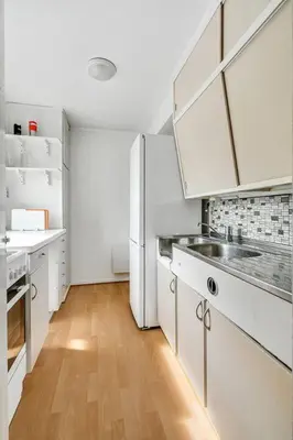a kitchen with a white refrigerator and a wooden floor at Fully equipped independent apartment near NTNU,Lerkendal og center in Trondheim
