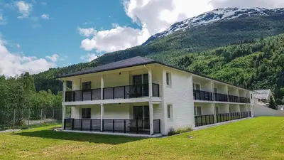 a large white building with balconies and a mountain at Loen Apartments in Loen