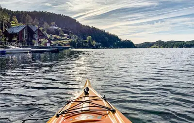 an orange kayak in the water near a dock at Amazing Home In Hebnes With Wifi in Hebnes