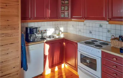 a kitchen with red cabinets and a sink and a stove at 4 Bedroom Stunning Home In Auklandshamn in Tjernagel