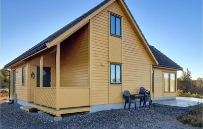 a house with two chairs in front of it at 4 Bedroom Stunning Home In Auklandshamn in Tjernagel