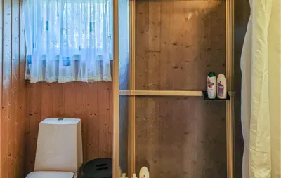 a bathroom with a toilet and a wooden wall at 4 Bedroom Lovely Home In Nordtveitgrend in Hjartåker