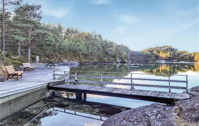 a wooden bench sitting on a dock next to a lake at 4 Bedroom Lovely Home In Nordtveitgrend in Hjartåker