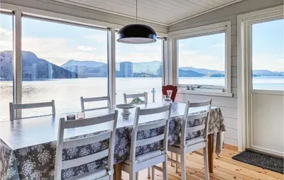 a dining room with a table and views of the water at 4 Bedroom Lovely Home In Nordtveitgrend in Hjartåker