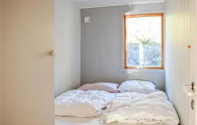 an unmade bed in a room with a window at 4 Bedroom Lovely Home In Nordtveitgrend in Hjartåker