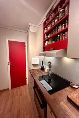 a kitchen with a red door and a kitchen counter at Cosy house with sunny terrace, garden and fjord view in Bergen